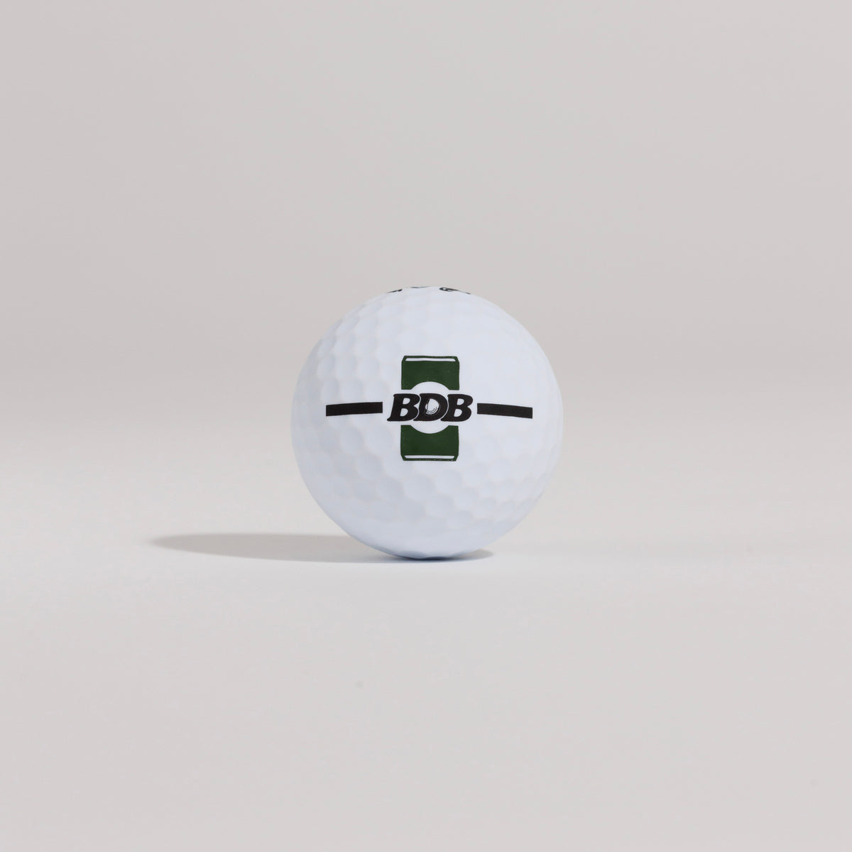 The Mulligan golf ball resting on a tee against a white background, showing BDB can putting and driving alignment tool