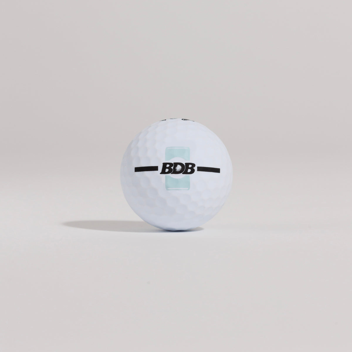 The Mulligan golf ball resting on a tee against a white background, showing BDB can putting and driving alignment tool