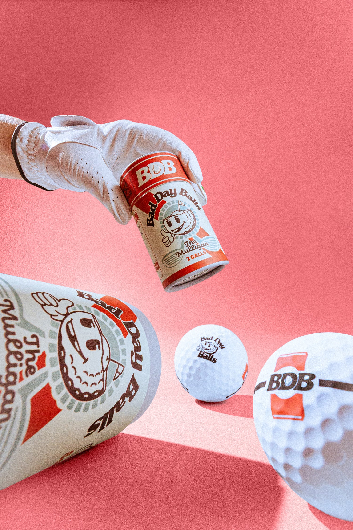 A white golf glove holds a branded bad day ball can above bad day balls 