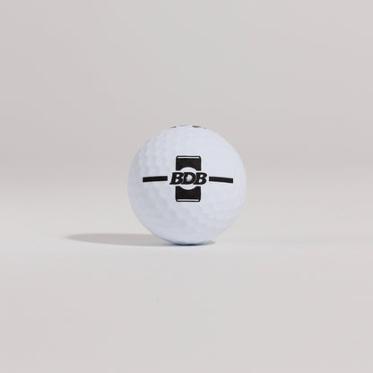 The Mulligan golf ball resting on a tee against a white background, showing BDB can putting and driving alignment tool 