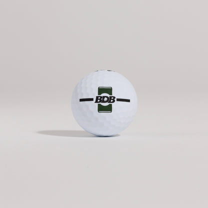 The Mulligan golf ball resting on a tee against a white background, showing BDB can putting and driving alignment tool