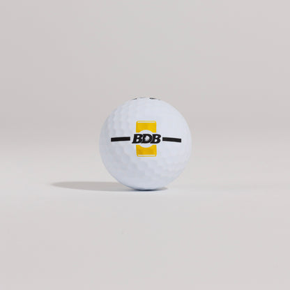 The Mulligan golf ball resting on a tee against a white background, showing BDB can putting and driving alignment tool