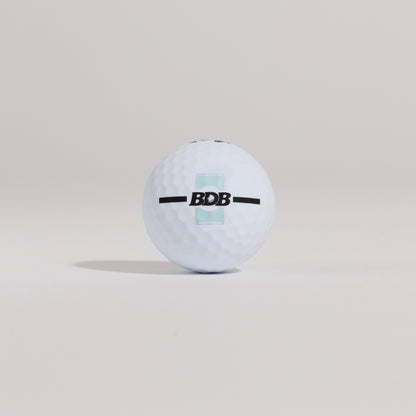 The Mulligan golf ball resting on a tee against a white background, showing BDB can putting and driving alignment tool
